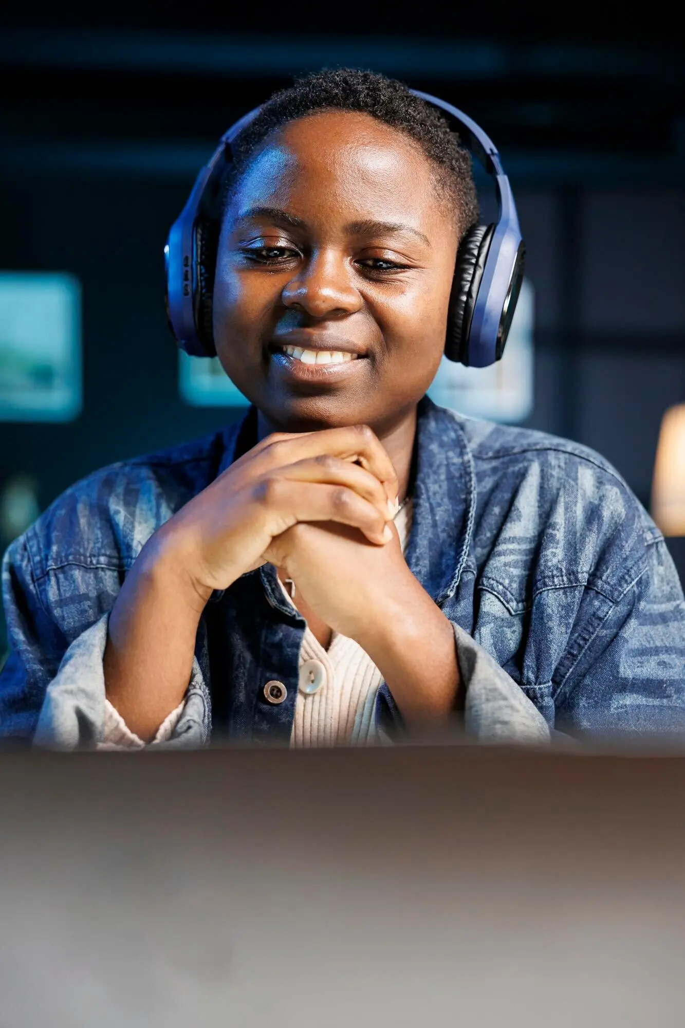 Eine Frau mit Kopfhörern blickt auf einen Laptop.